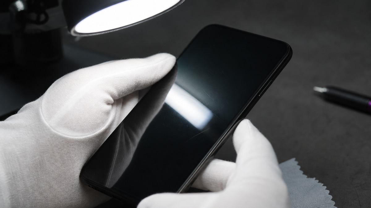 スマートフォンの外装の傷を明るい光の下で確認している様子
