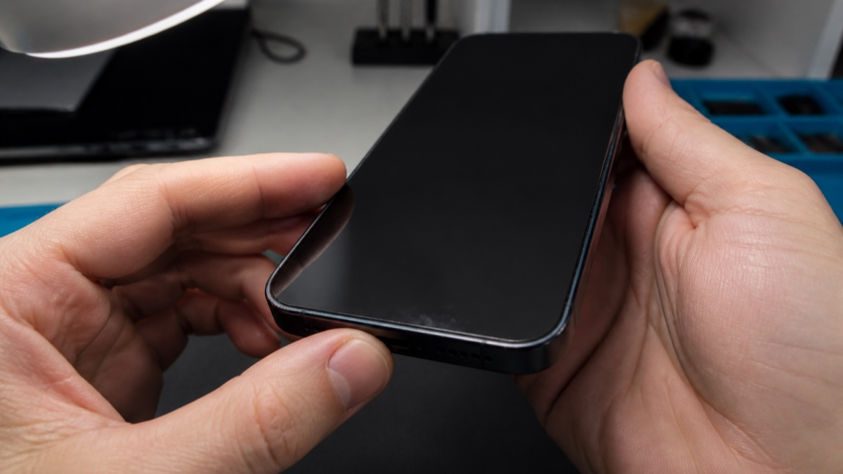 中古スマートフォンの外装の傷を明るい光の下で確認している手元