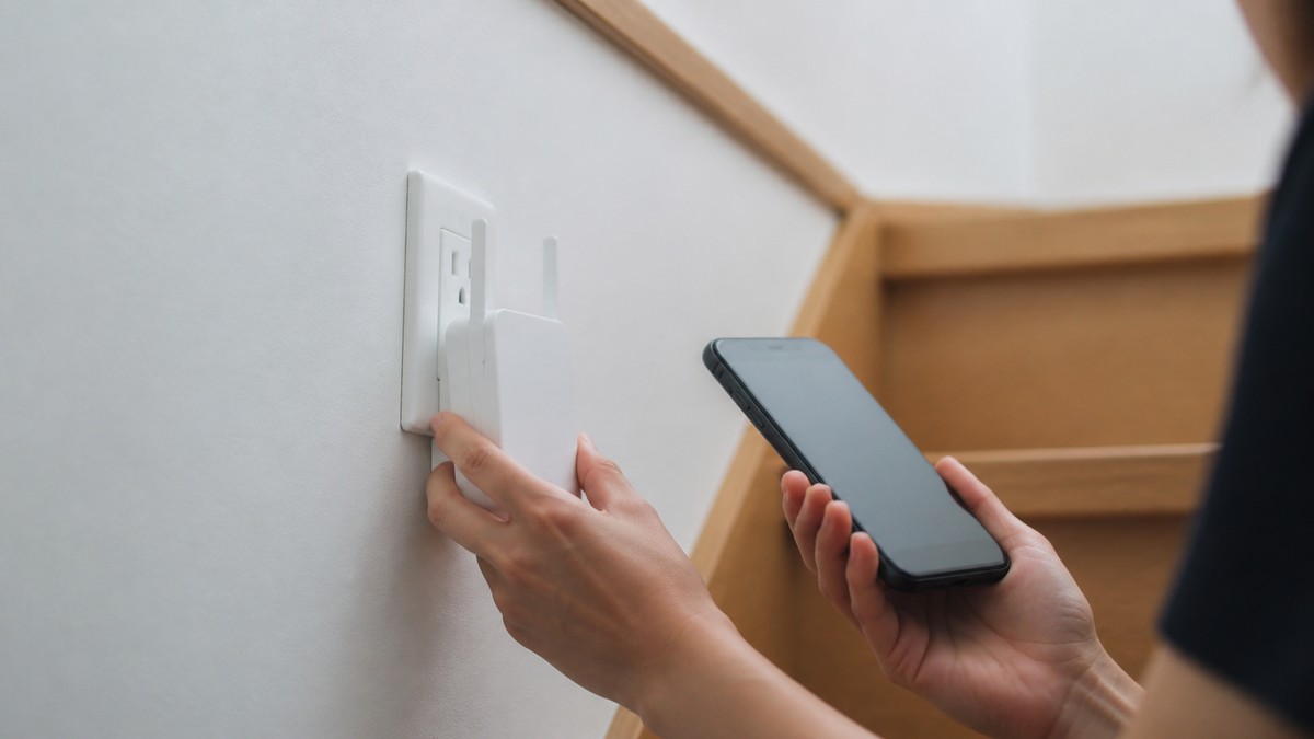 階段の途中のコンセントにWi-Fi中継機を設置しているところ
