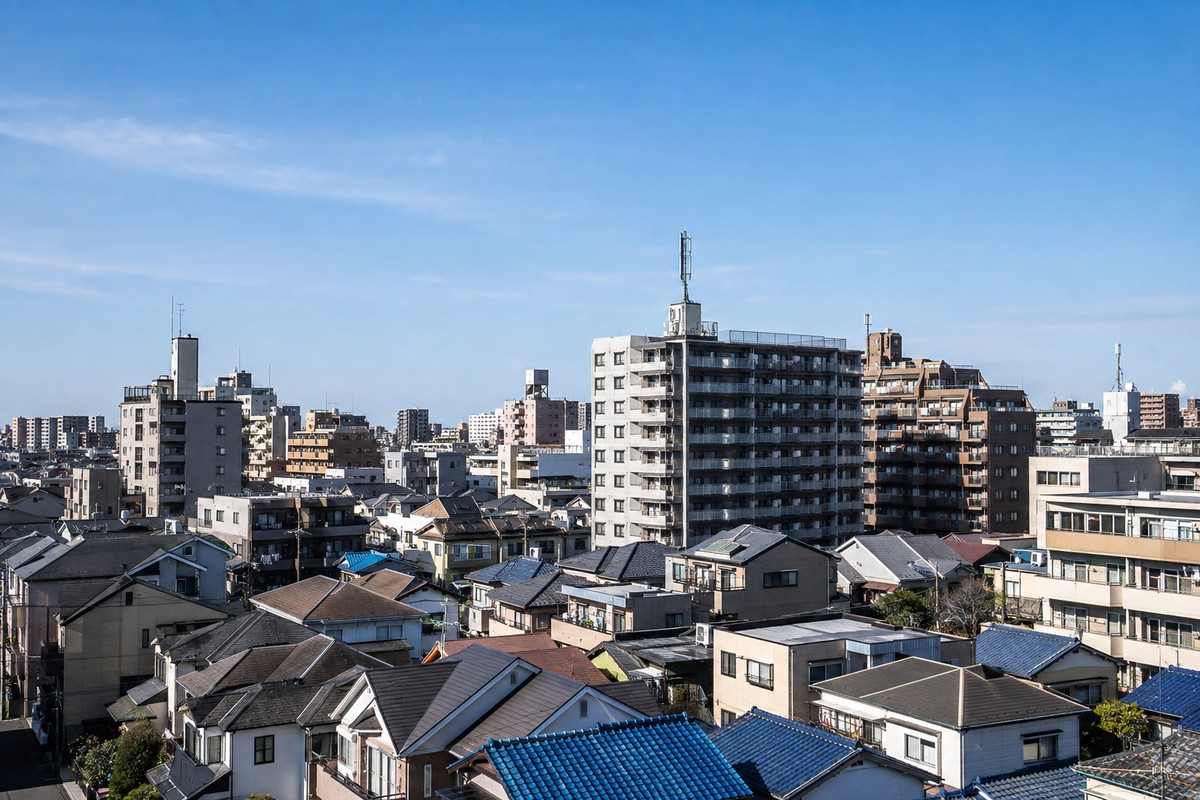 住宅街とマンションの屋上に設置された携帯電話基地局アンテナ