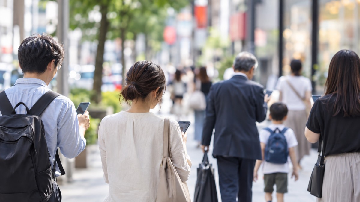 街中でそれぞれスマートフォンを使う人たち