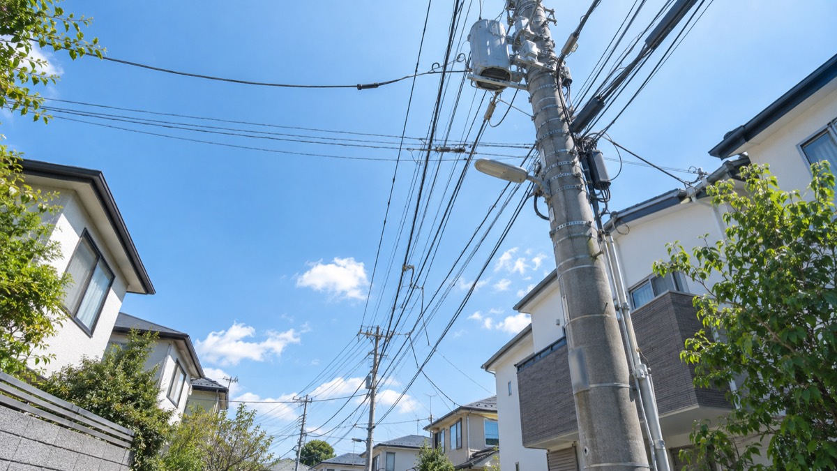 住宅街の電柱から各戸へ伸びる光ファイバーケーブル