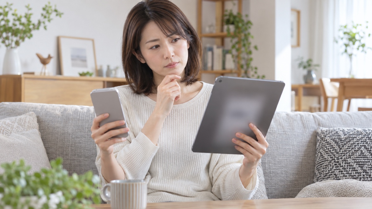 スマートフォンとタブレットを持って補償を考える女性